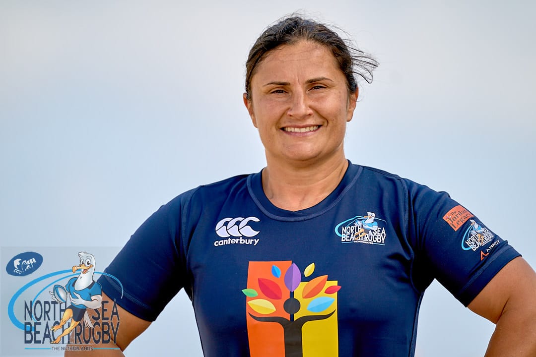 Smiling rugby athlete in blue sportswear North Sea Beach Rugby poses outdoors with confidence