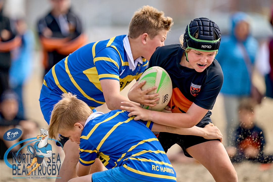 Youth rugby players compete energetically Youth rugby players compete energetically on sandy beach during tournament