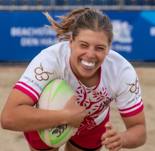 Two female players from the Dutch national beach rugby team posing in orange team kit.