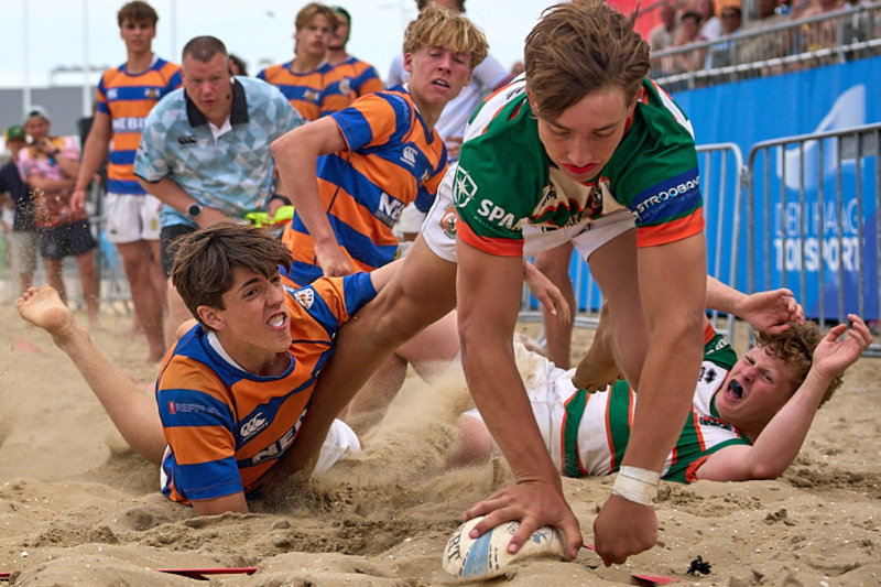 Beach rugby player scores try in sand during match
