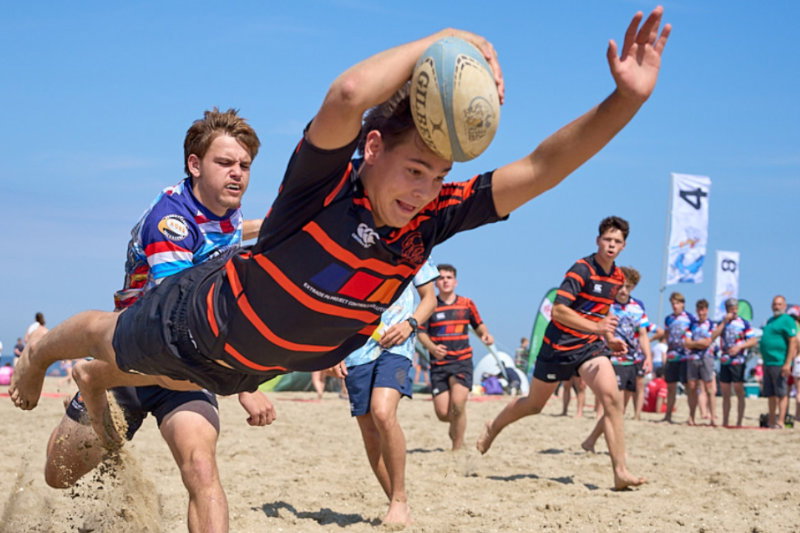 Beach rugby player diving for try on sandy shore